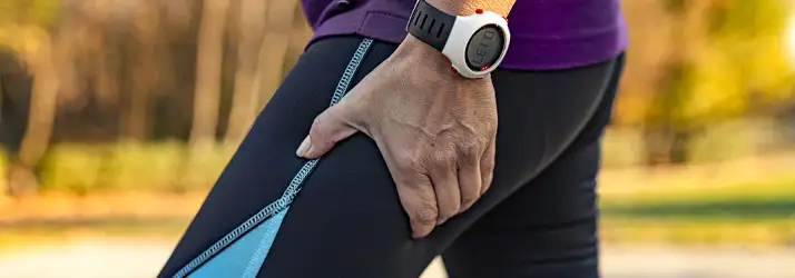 Concussion Irvine CA Leg Pain A close up of a person holding their thigh while wearing leggings.